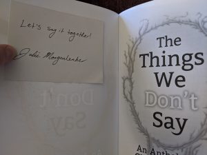 White card on inside cover of book and title page to the right. Text on card "Let's say it together!" and signature beneath text.
