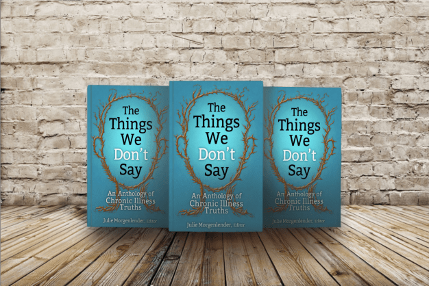 The copies of book The Things We Don't say lined up in front of a white brick wall